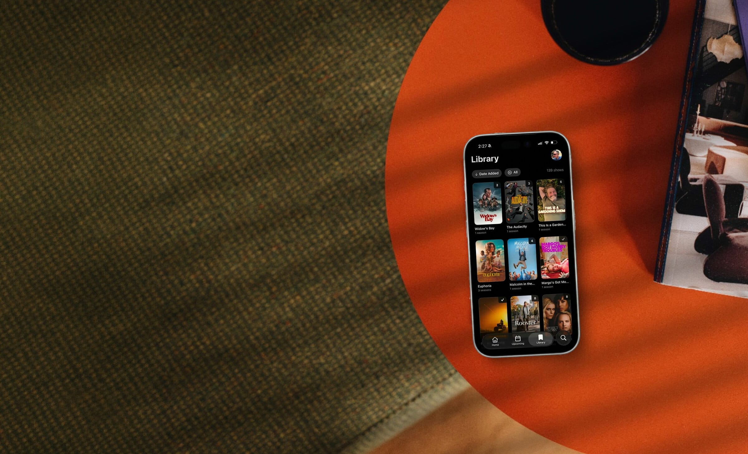 NextUp running on an iPhone, sitting on an orange table.