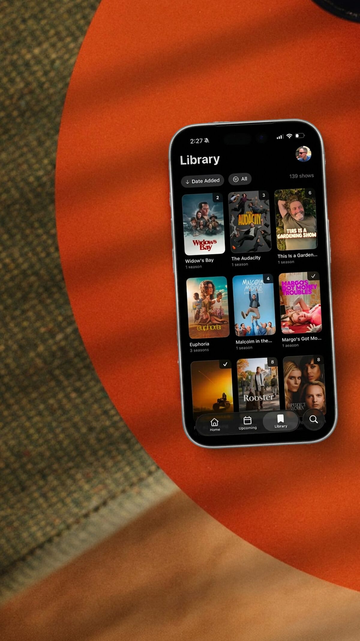 NextUp running on an iPhone, sitting on an orange table.